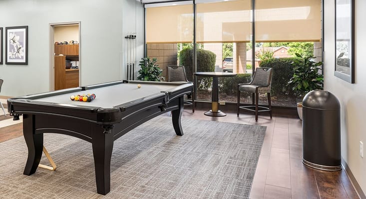Billiards table in a common area with seating and large windows