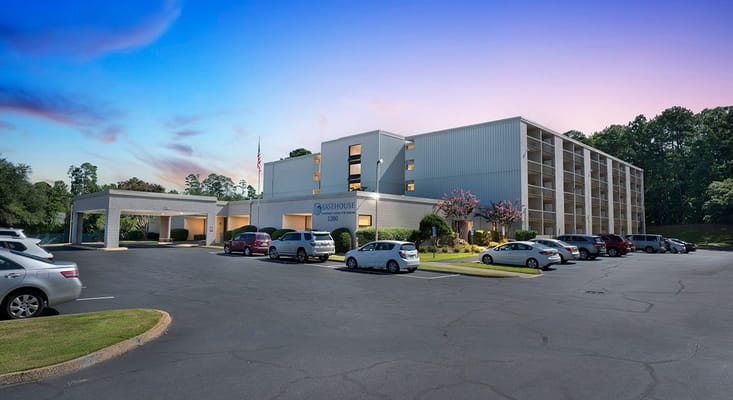 Exterior of Easehouse Senior Apartments with parking lot and trees.