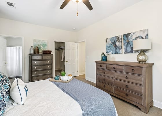 A spacious bedroom featuring a queen-sized bed, dresser, and decorative artwork.