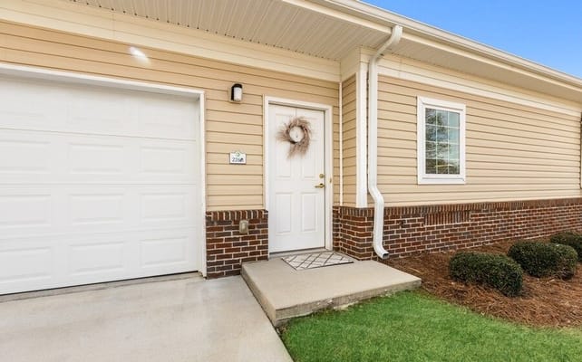 Front entrance of a unit at Summer Village Camellia Place with a door and garage.