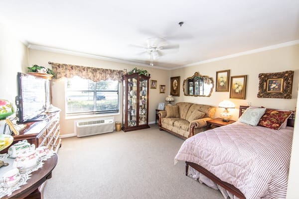 Spacious bedroom with a bed, sofa, and display cabinet.