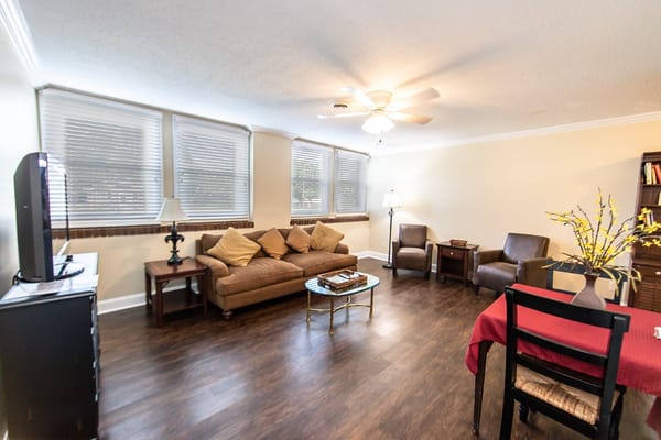 A cozy living room with a sofa, chairs, and a television in Riverside Senior Living.
