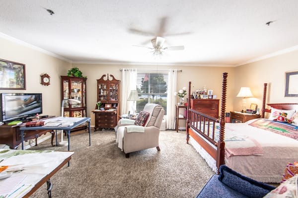 Well-furnished bedroom in Riverside Senior Living with a bed and seating area.