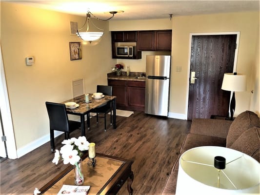 A living room with a sofa, dining table, and kitchenette.