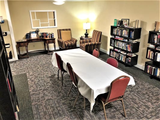 Library room with a table and chairs, a lamp, and bookshelves.