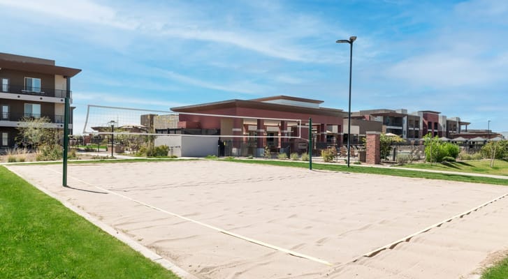 Sand volleyball court surrounded by greenery and buildings