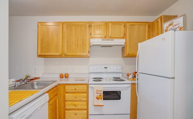 Bright kitchen with wooden cabinets and white appliances.