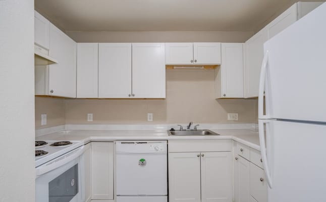 Bright and modern kitchen with white cabinets and appliances.
