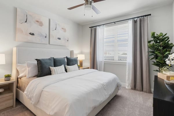 A stylish bedroom with a large bed, decorative pillows, and natural light