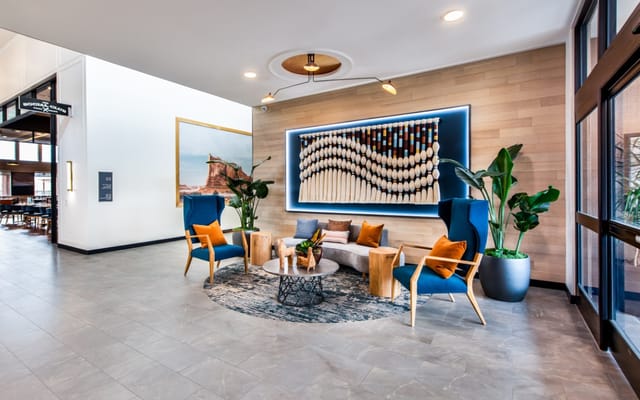 Modern lobby with blue chairs, artwork, and plants.