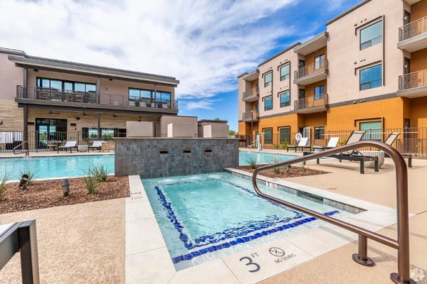 Outdoor pool area with lounge chairs and buildings in background