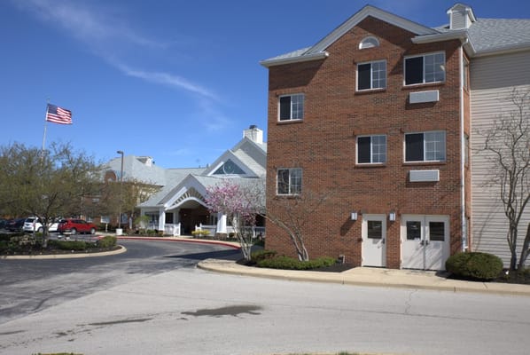 Building exterior of a senior living facility with trees and parking
