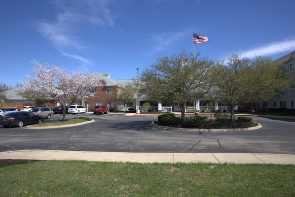 Exterior view of a senior living facility with trees and flag