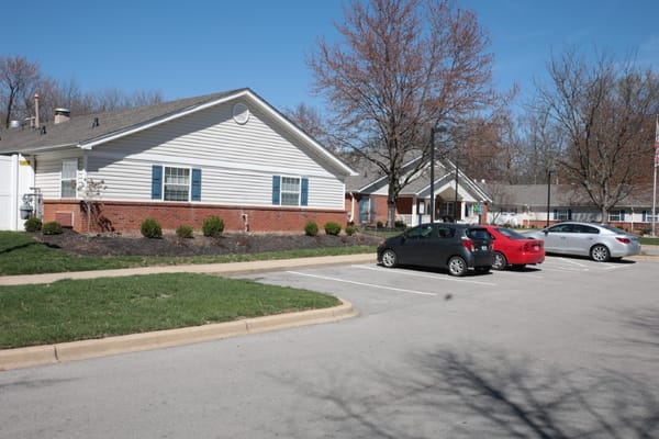 Parking lot with vehicles near a senior living building.