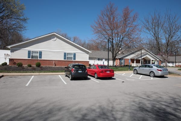View of parking area with three cars and residential buildings.