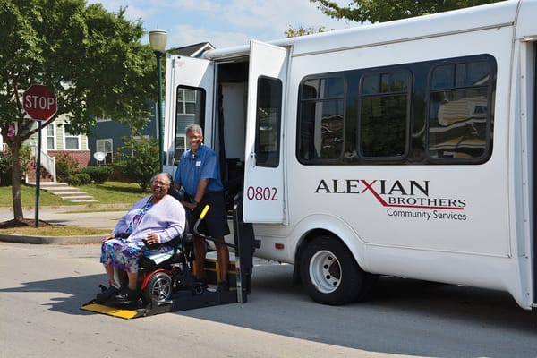 Resident boarding a community transport vehicle with staff assistance