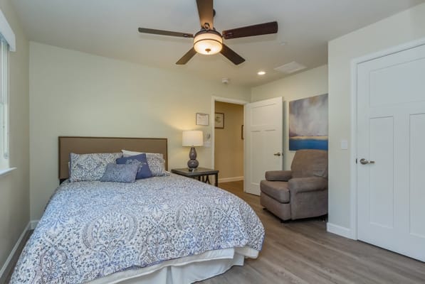 A cozy private resident room with a bed and armchair