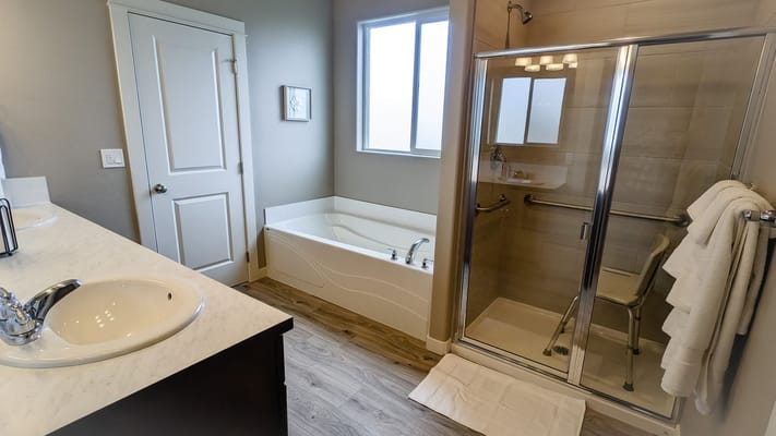A modern bathroom featuring a tub and a shower with glass doors.