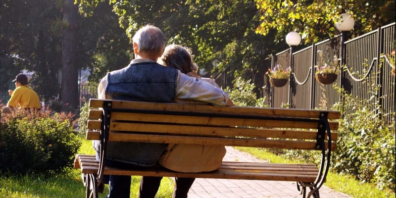 Senior couple sitting on a bench in a garden