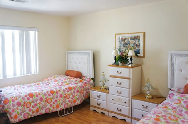 A cozy shared bedroom with floral bedding and lamps.