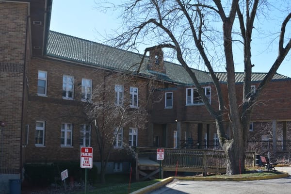 Facade of Villa Maria Retirement Community with trees and no parking signs