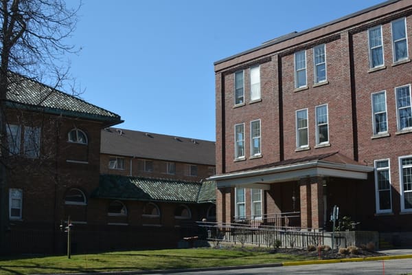 Facade of Villa Maria Retirement Community featuring brick buildings and a green roof.