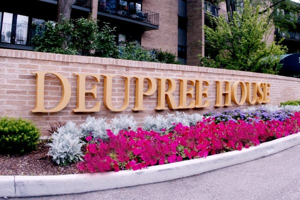 Exterior sign of Deupree House with flowers in front