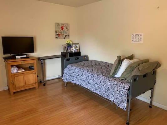 A cozy bedroom with a bed, TV, and bedside table.
