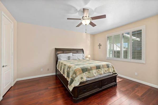 A cozy bedroom setup with a large bed and wooden flooring