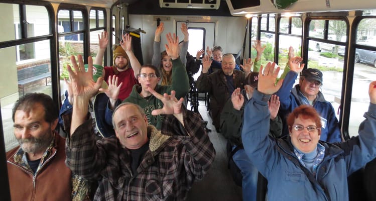 Residents happily waving on a facility transport bus