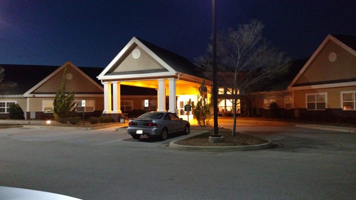 Well-lit entrance of Grandview Gardens senior living facility at night