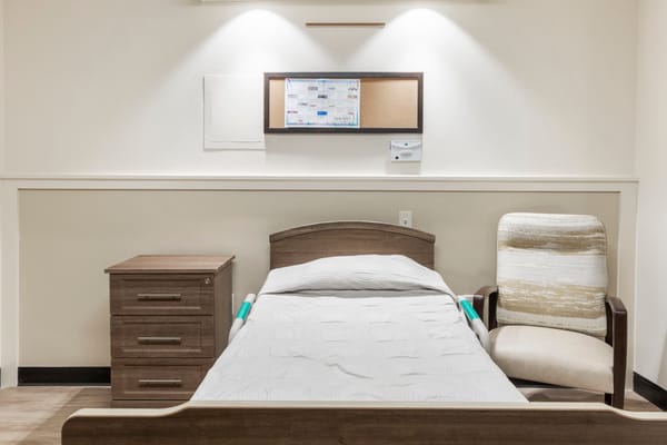 A private resident room with a bed and chair