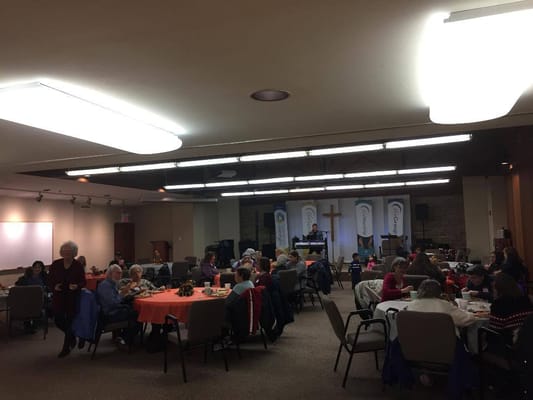 Seniors enjoying a community event with orange tablecloths and food