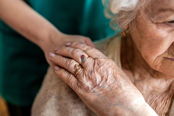 Caregiver's hand resting on a resident's shoulder