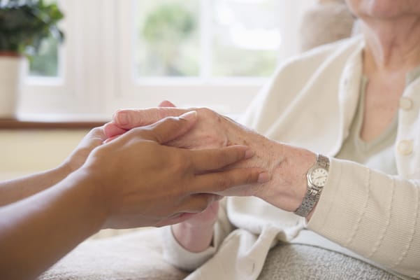 Caregiver holding a senior's hand in a warm setting