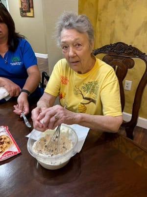 Resident baking cookies with staff assistance