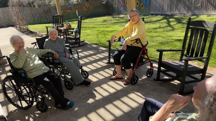 Residents enjoying time in an outdoor space with rocking chairs