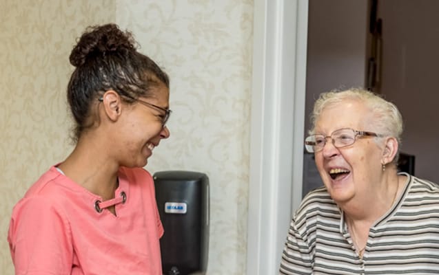 Staff member and resident sharing a joyful moment indoors