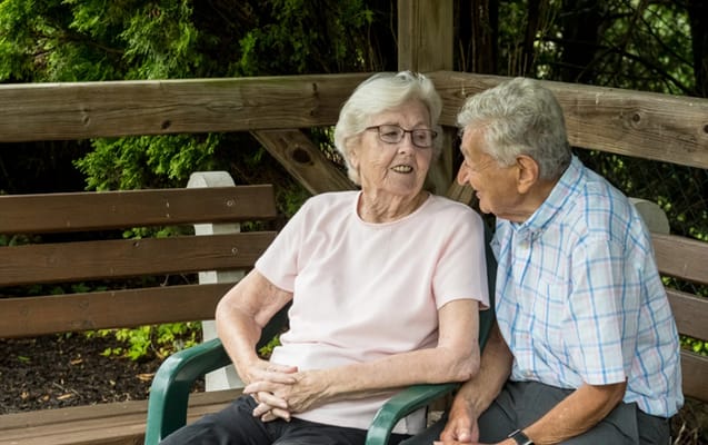 Residents enjoying a conversation on a bench outdoors