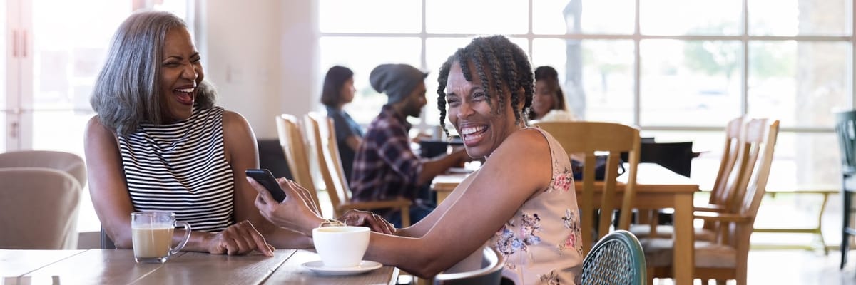 Two women laughing at a table in a dining area