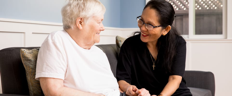 A caregiver and resident engaging in conversation on a couch