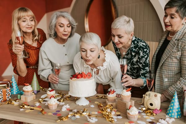 Women celebrating a birthday with a cake and drinks