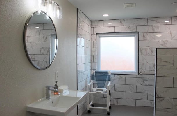 Bright bathroom with modern fixtures and a shower chair