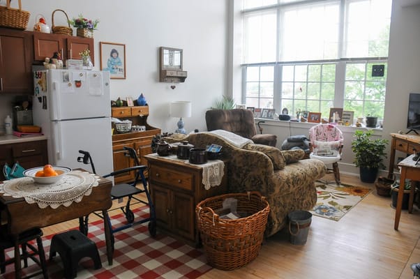A cozy living room with a comfortable chair, a dining table, and bright windows.