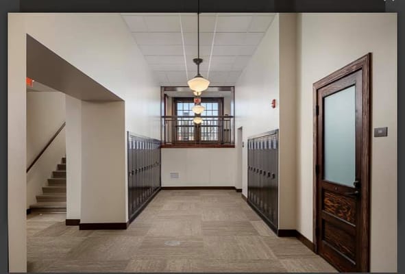 Well-lit hallway with lockers and a staircase