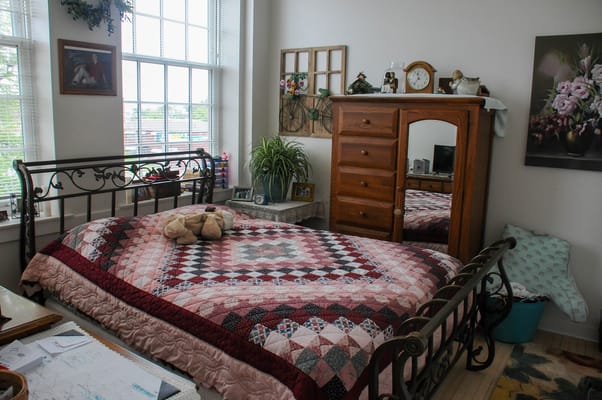 An inviting bedroom with a quilted bedspread and wooden furniture.
