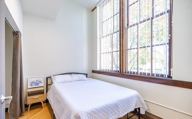Bright private room with a bed and large windows