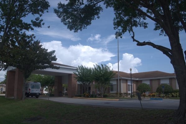 Exterior view of the facility with trees and a vehicle