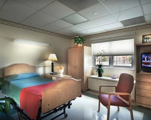 A cozy bedroom featuring a bed, lamp, and a chair with a view.