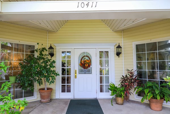 Front entrance of St. Francis Villa with potted plants and a seasonal wreath.